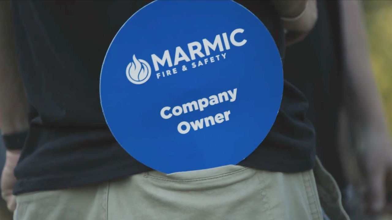 An employee holds a small sign that says "Company Owner" in their back pocket 